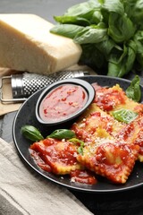 Delicious ravioli with tomato sauce, cheese, grater and basil on grey table, closeup