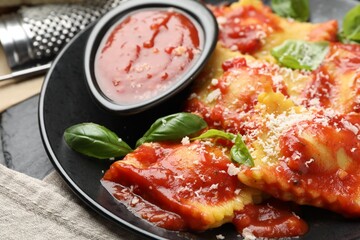 Delicious ravioli with tomato sauce, cheese and basil on grey table, closeup