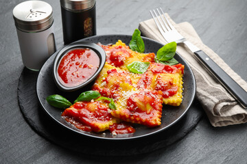 Delicious ravioli with tomato sauce, cheese and basil served on grey table, closeup