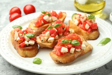Tasty bruschettas with mozzarella cheese, tomatoes and basil on grey textured table, closeup