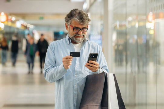 Process of online payment by using credit card and smartphone. Senior man is in the mall, shopping time conception