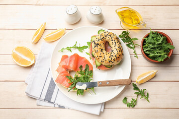 Delicious bagels with salmon served on wooden table, flat lay