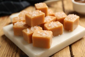 Tasty caramel candies with salt on wooden table, closeup