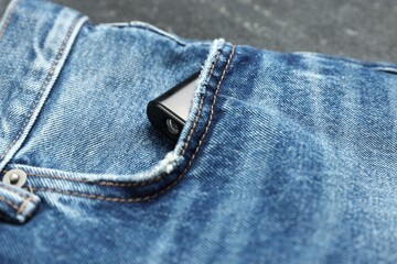 Hidden spy camera in pocket of jeans on black background, closeup