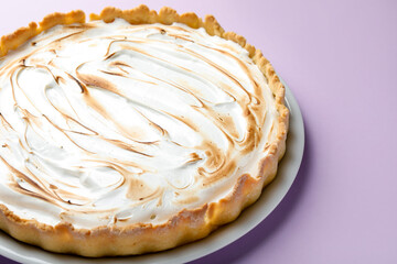 Tasty lemon meringue tart on lilac background, closeup