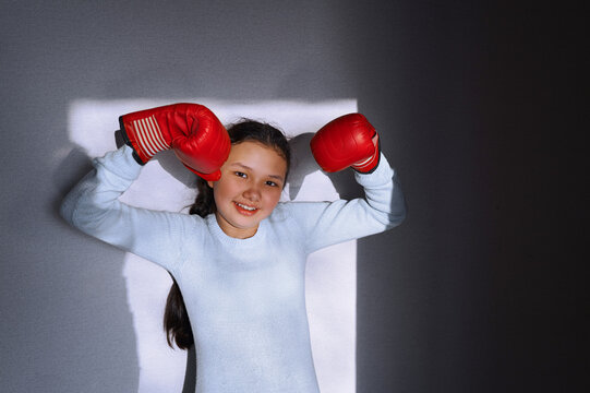 Smiling girl with red boxing gloves indoors