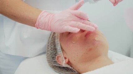 Woman lying calm during skincare session as cosmetologist applies cream to face. Female receiving professional care focused on nourishing and hydrating skin. Girl enjoying relaxing beauty treatment - Powered by Adobe