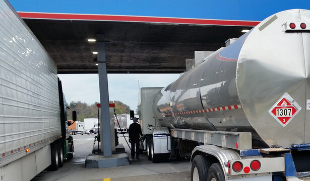 Tank truck with flammable hazmat placard at truck stop fuel island.  Resubmission.