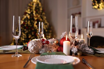 Stylish Christmas table setting with plates, glasses and burning candles in festive decorated room, closeup. Bokeh effect