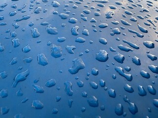 glossy blue surface is covered with numerous water drops, which create a dynamic and material visual effect.