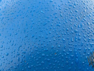 glossy blue surface is covered with numerous water drops, which create a dynamic and material visual effect.