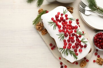 Tasty Christmas cake with cranberries and rosemary served on light wooden table, flat lay. Space for text
