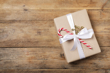 Decorated Christmas gift with candy cane on wooden background, top view. Space for text