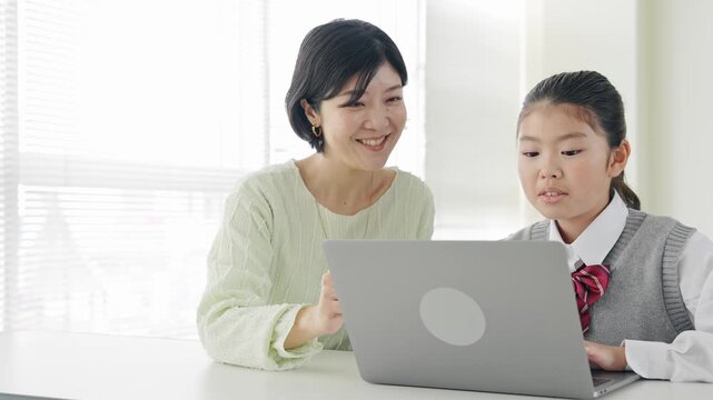 教室で女性教員からパソコンを教わる女の子