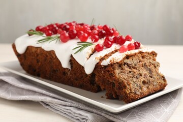 Tasty Christmas cake with icing, cranberries and rosemary on white wooden table, closeup