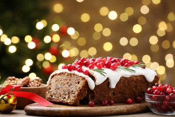 Tasty Christmas cake with icing, cranberries and rosemary on wooden table against background with blurred lights, closeup