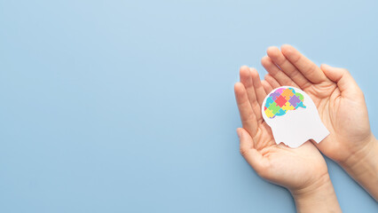 World autism awareness day concept. Hands holding human head shape with colorful jigsaw puzzle...