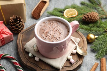 Tasty cocoa, marshmallows, cinnamon, candy cane and Christmas decor on grey table, closeup