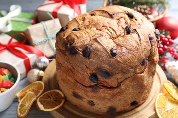 Tasty Christmas panettone cake, dry orange slices and gift boxes on table