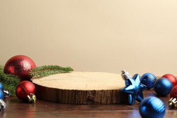 Empty podium and Christmas decor on wooden table against beige background, closeup. Space for text