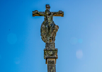 Ancient Stone Cross with Religious Sculpture Against Blue Sky
