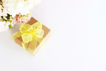 Gift box with yellow bow and beautiful bouquet of white hydrangeas flowers on white background. Gift for holiday, birthday, Wedding, Mother's Day, Valentine's day, Women's Day. Floral arrangement