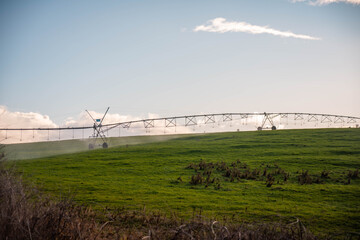 pivot irrigation on a hill farm growing pasture crop in a field irrigation with water from a river....