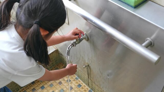 Girl washing her hands at the tap