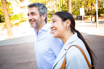 Cheerful couple smiling and walking side by side during a sunny day outdoors