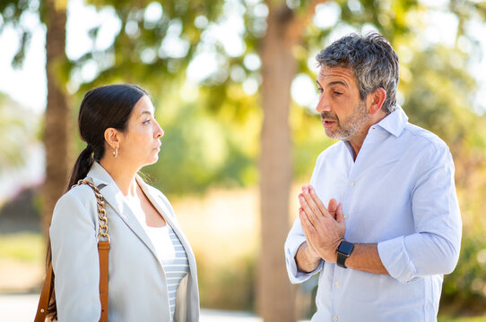 Man apologizing to woman during a serious outdoor conversation