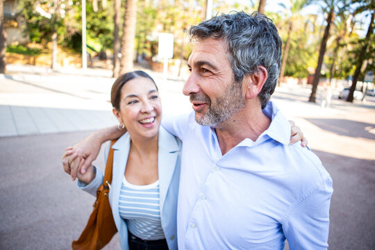 Smiling couple walking together arm in arm and enjoying a joyful conversation - Powered by Adobe