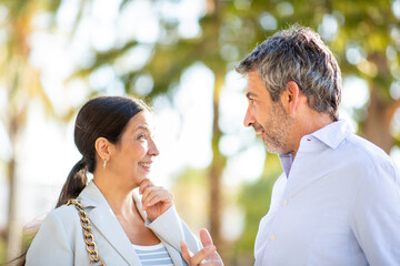 Happy middle-aged couple talking outdoors on a sunny day