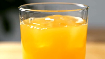 Refreshing orange juice being poured into a glass with ice cubes creating a splash and a - Powered by Adobe