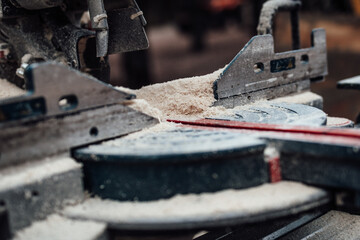 Close-up view of a precision cutting tool covered in sawdust, showcasing the intricate mechanics and craftsmanship involved in woodworking and carpentry projects