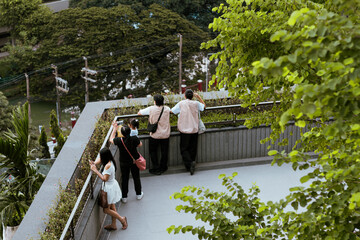 Visitors relax and take photos of Bangkok’s vibrant urban landscape from Dusit Central Park. The green space offers a refreshing contrast to the bustling city.