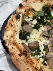 Artisanal pizza with a high, golden crust, with a light browning typical of wood-fired oven cooking. The center is filled with rich, flavorful toppings.