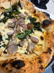 Artisanal pizza with a high, golden crust, with a light browning typical of wood-fired oven cooking. The center is filled with rich, flavorful toppings.