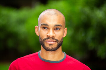 Young man in red shirt looking at camera outdoors