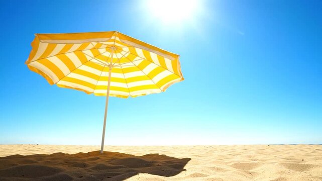 Sunny beach striped yellow umbrella, blue sky, light reflecting off the sand