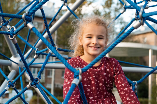 Girl smiling while playing on outdoor climbing frame