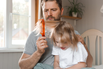 Man brushing daughters hair. Daddy combing girl's hair at home. Responsible good dad braiding his child girl's hair. Handsome father grooming his little one. Morning routine concept. Family life