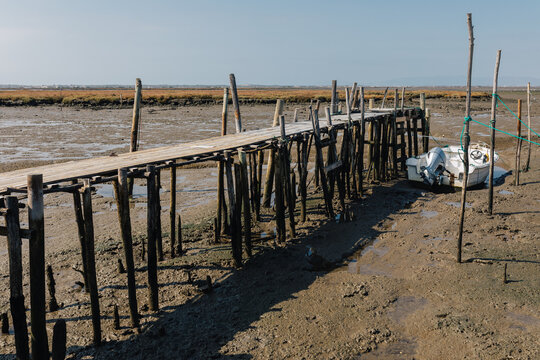 Wooden pier on dry sea bed with abandoned boat