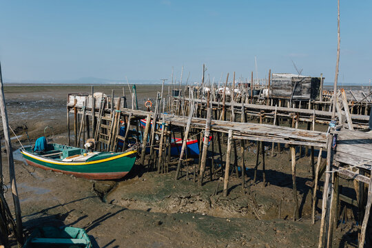 Boats stranded on a dry sea under wooden pier structures