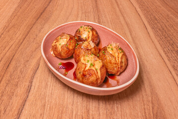 Octopus takoyaki with tender pieces of octopus, red ginger, and chives, cooked in a special pan with holes