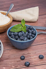 Some blueberries roll freely across the oak surface, stopping against the knots and natural irregularities of the board.