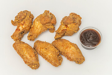 A close-up shot showing the golden, bubbling texture of the fried chicken wings, with drops of thick barbecue sauce