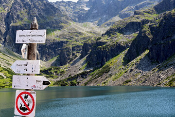 Black Pond (Czarny Staw Gasienicowy) – a glacial lake in the High Tatras, 1620 m above sea level. Tatra National Park, Poland. Tourist information board with tourist routes. Signpost on hiking trail.