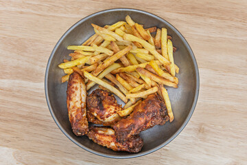 Fried chicken wings with julienne fries and blue buffalo sauce, accompanied by celery and carrot sticks with ranch dip.