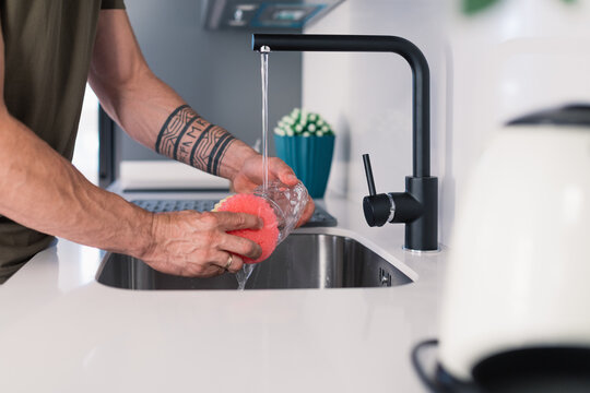 Man washing dishes in modern kitchen setting