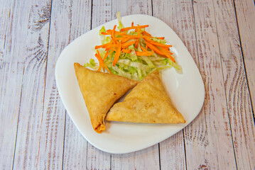 The promise of a crispy bite: a close-up of a perfectly golden samosa, its thin layer of crumbly pastry about to burst
